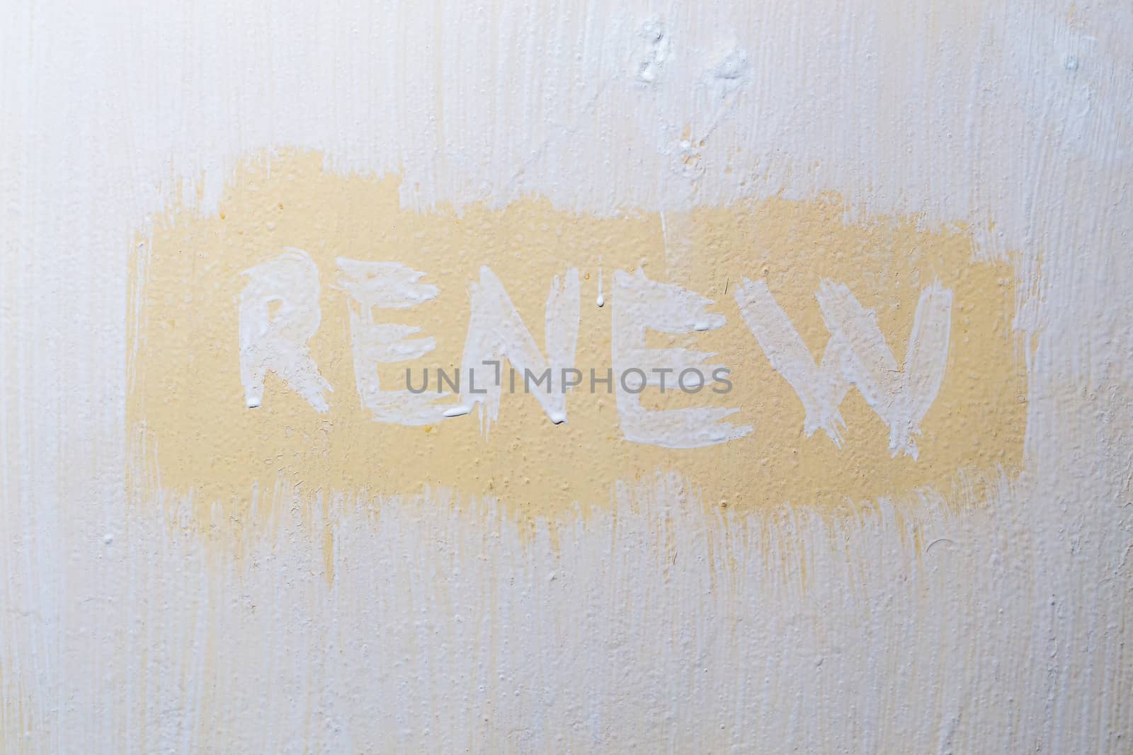 the word renew written with fresh paint over old flat painted surface.