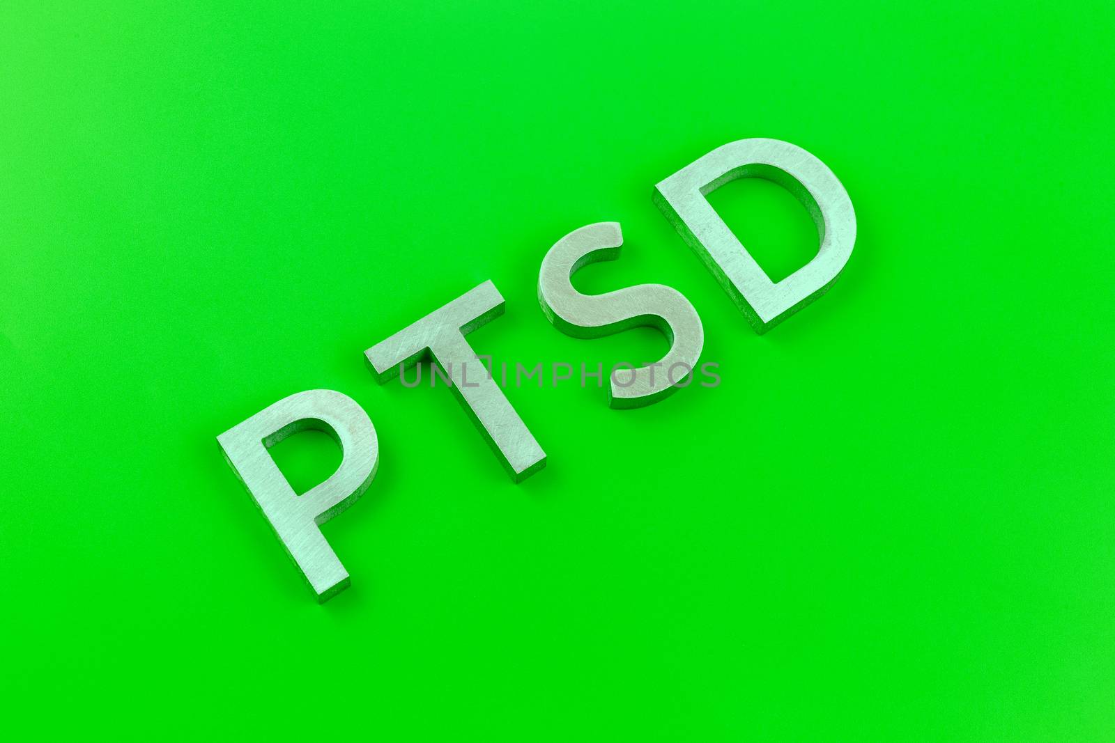 abbreviation PTSD - post traumatic stress disorder - laid with silver metal letters on acid green flat surface by z1b