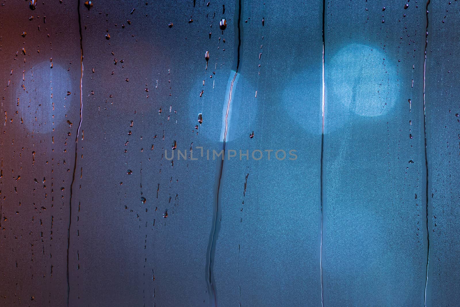 an abstract background of night wet window glass with smudges in blue tone gamma.