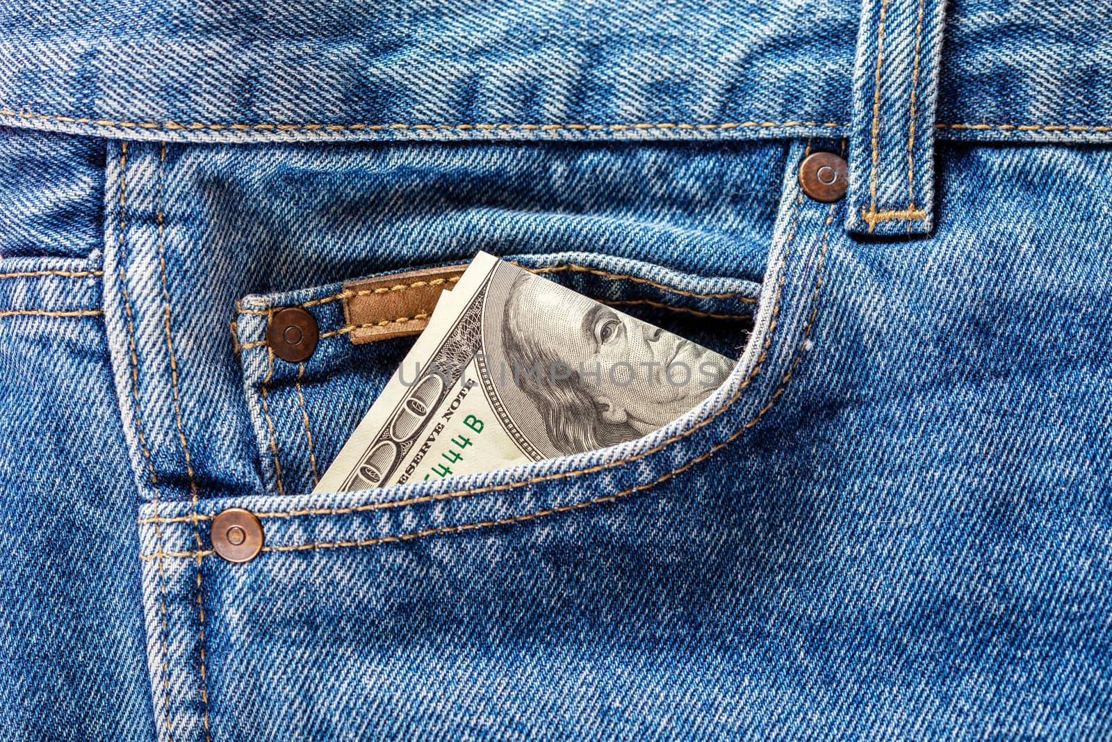 a hundred dollar banknote sticking out from front pocket of jeans - close-up