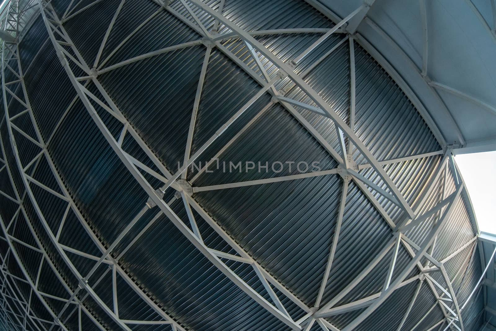 A heavy distortrd fish-eye lens picture of industrial ceiling with supporting beam construction frame and profiled sheets. Zenith direction of view.