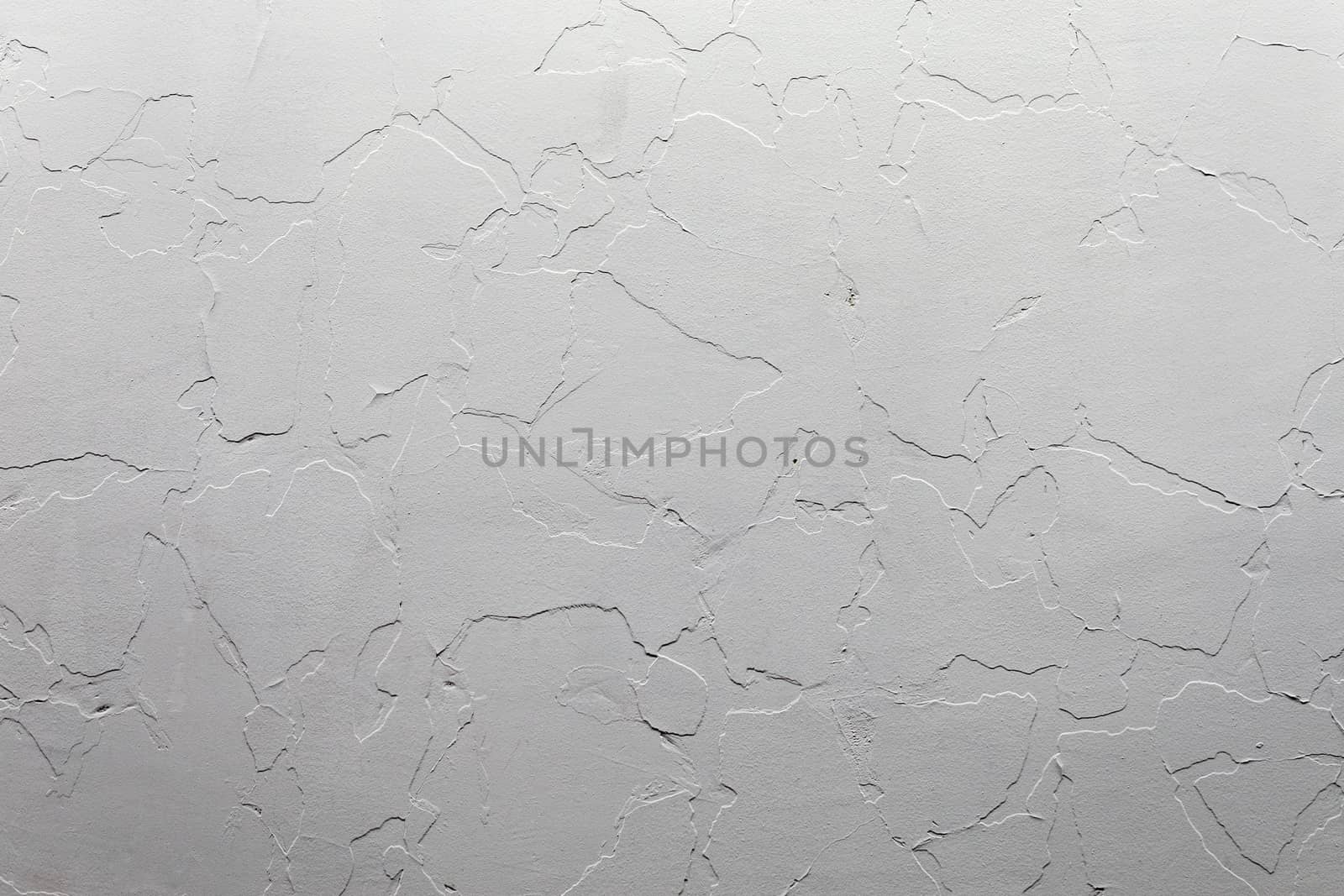 Abstract white unostentatious background and texture. A plaster wall with old cracked layer under new one. Top-down light direction.