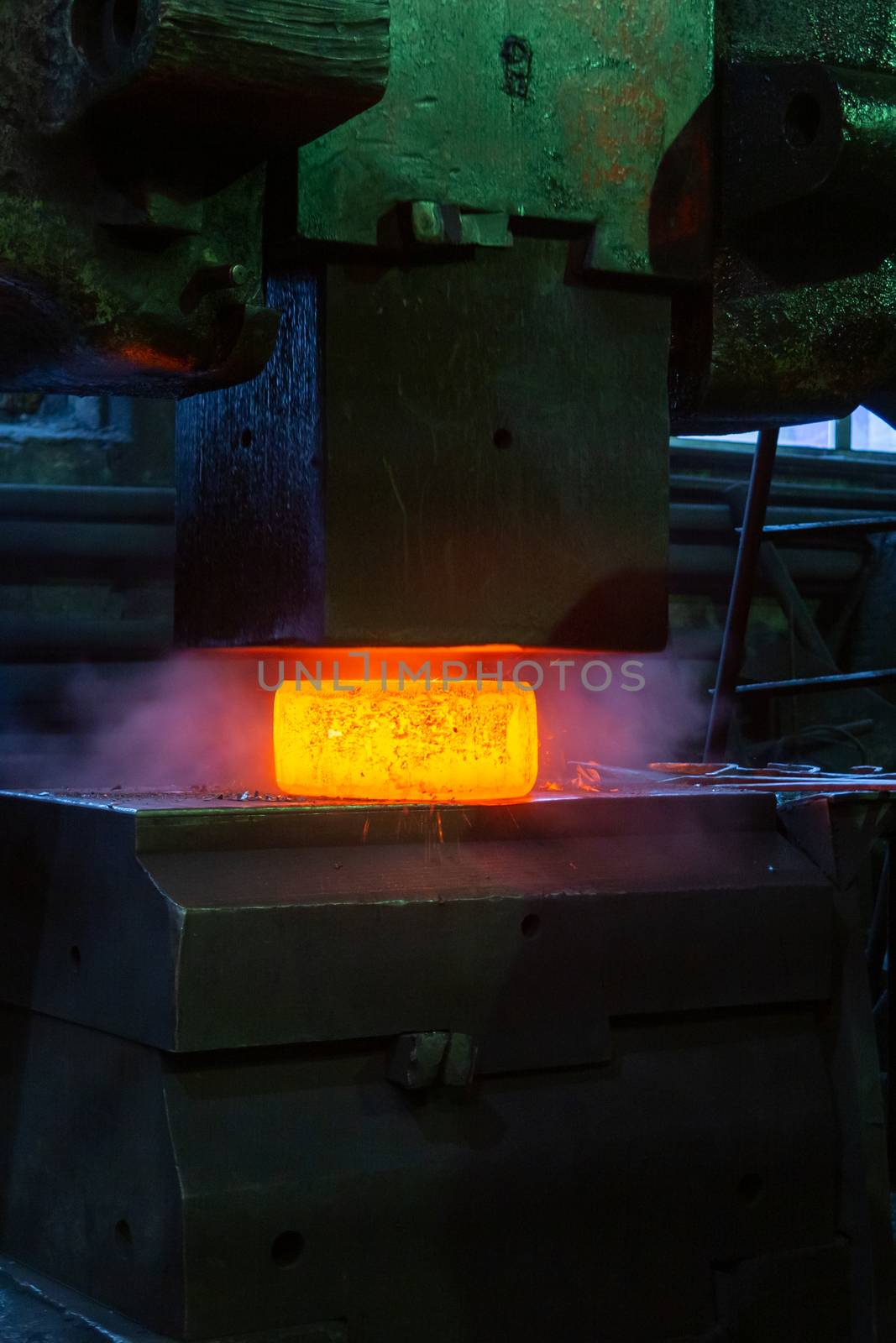 close-up picture of hot steel manual forging process with big mechanical hammer machine, sparks flying out from workpiece