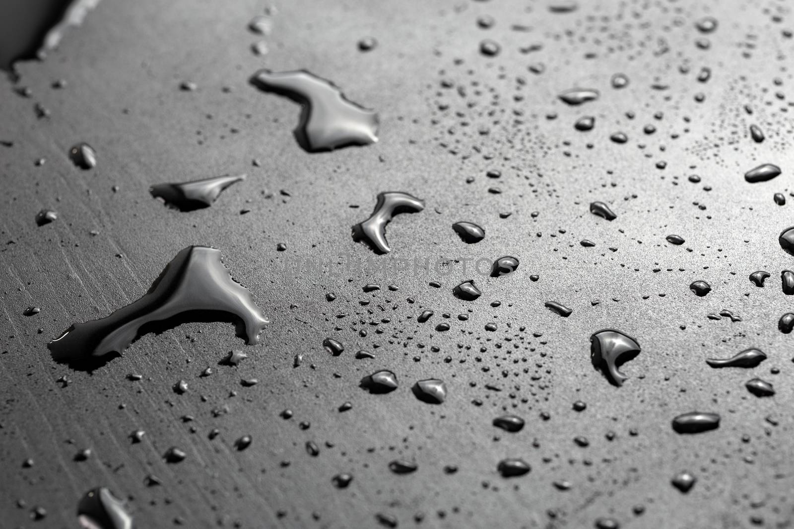 abstract background of wet black hydrophobic surface - close-up with selective focus and skewed perspective