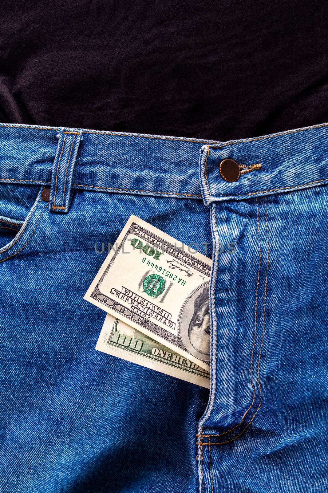 a two hundred dollar bills inside a fly of blue jeans close-up with selective focus by z1b