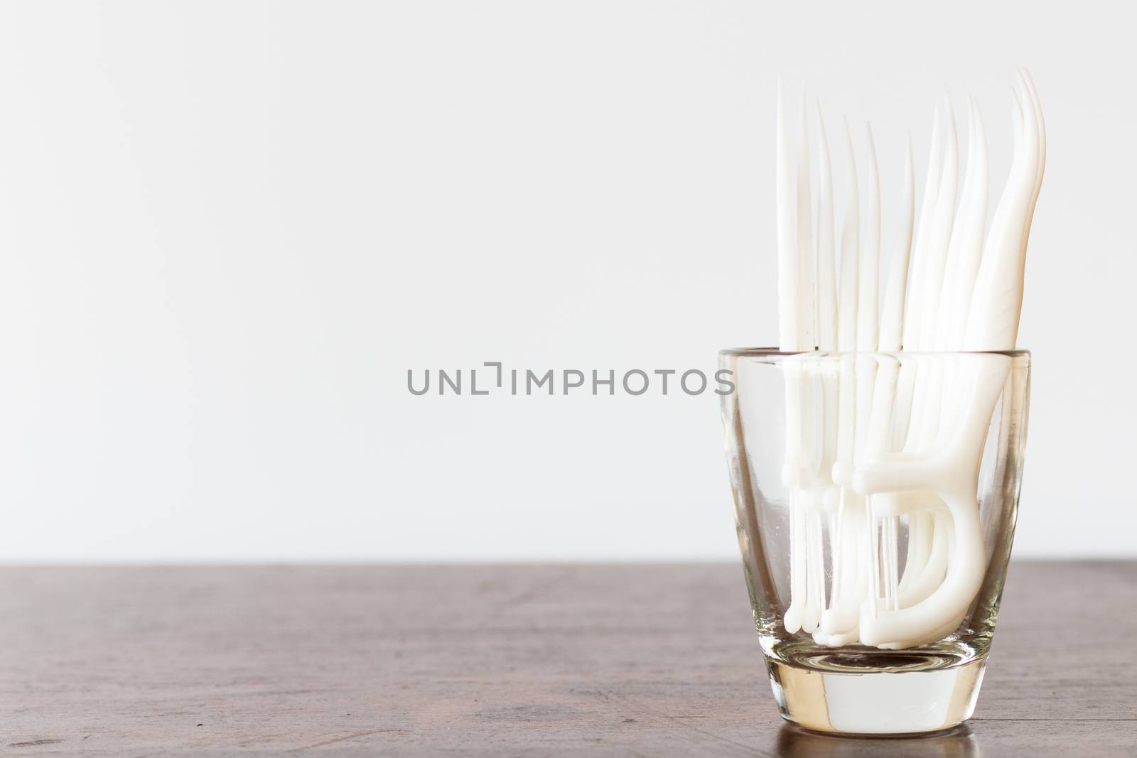 Oral Device : Dental floss in glass on wooden background by sirichaiyaymicro