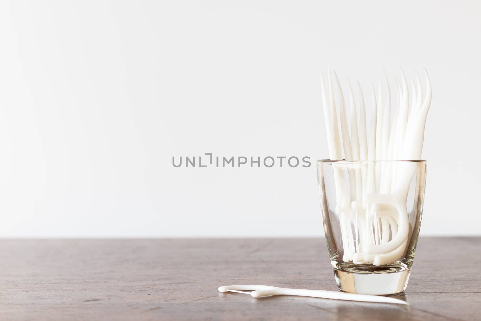 Oral Device : Dental floss in glass on wooden background by sirichaiyaymicro