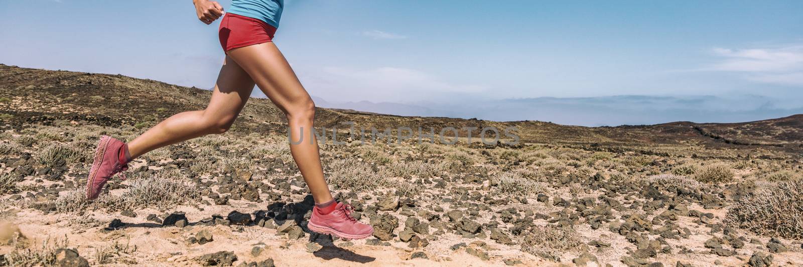 Sport exercise fitness female athlete runner running on trail run race in desert panorama banner. Closeup of legs and running shoes.