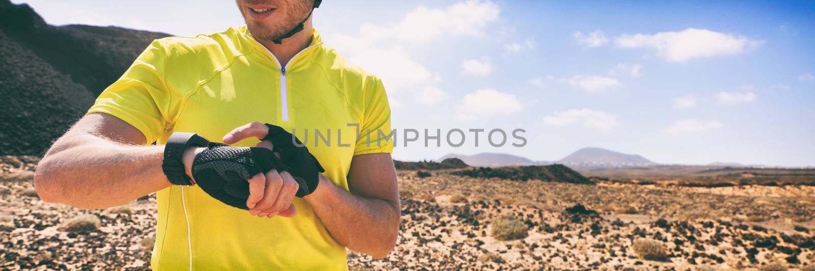 Biking cyclist on mountain bike using wearable tech device smart watch on outdoor training. Panoramic banner man athlete active lifestyle.