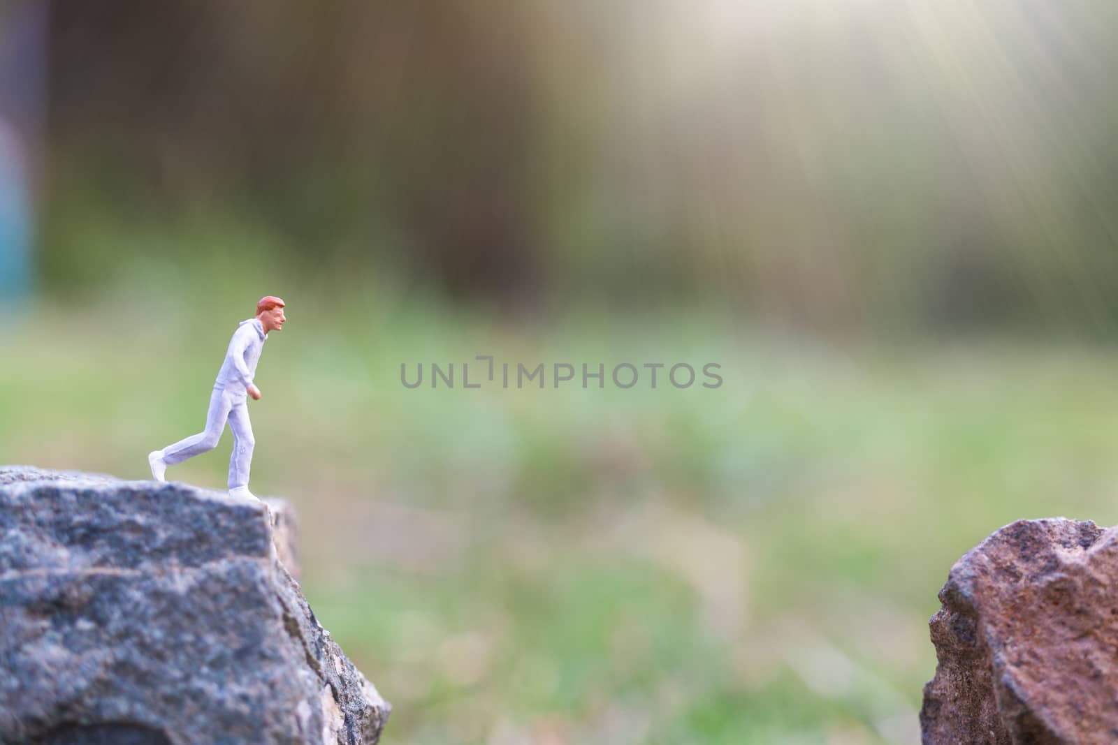 Miniature people : Running on rock cliff with nature background , Health And lifestyle concepts
