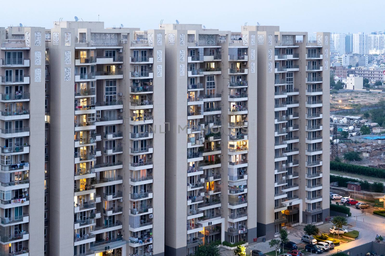 Aerial dusk shot of buuldings with warm orange lights shining out of the newly constructed homes offices and residences . Shows the elegance and opulence of the real estate sector in cities like Gurgaon, Mumbai, Jaipur, bangalore, mumbai and more