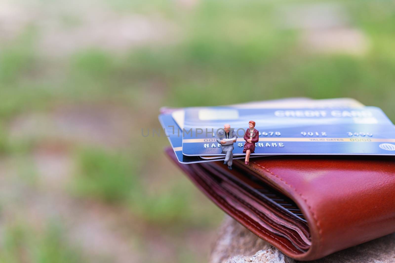 Miniature people : business people sitting on Credit card by sirichaiyaymicro