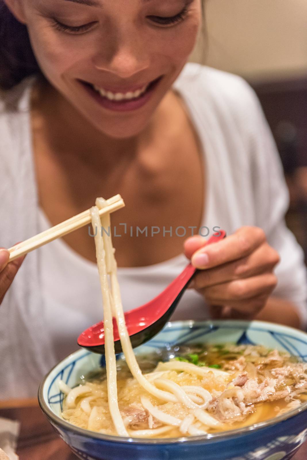 Ramen noodles girl eating soup bowl at japanesese restaurant at night. City travel lifestyle. by Maridav