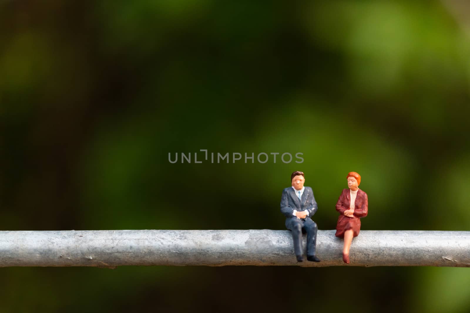 Miniature people : business people sitting on a  wire with green background 
, Business  team concepts