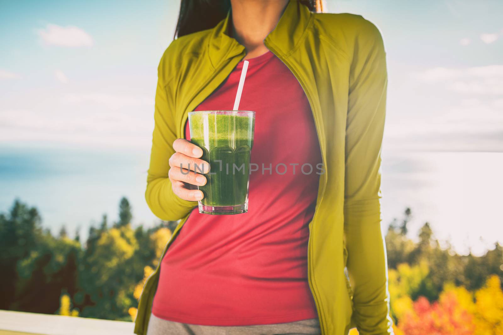Green smoothie breakfast detox diet food cleanse juice drink. Woman eating healthy for weight loss, morning meal outside in autumn nature.