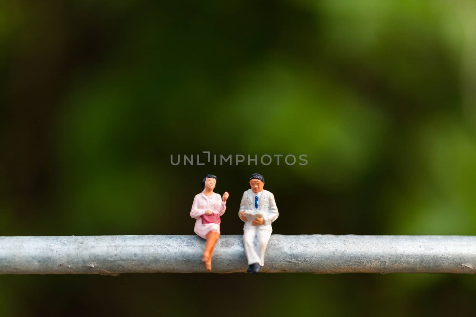 Miniature people : business people sitting on a  wire with green background 
, Business  team concepts