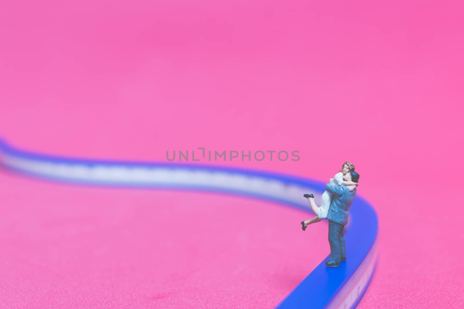 Miniature people : Couple hugging on The bridge on pink background , Valentine's day concept