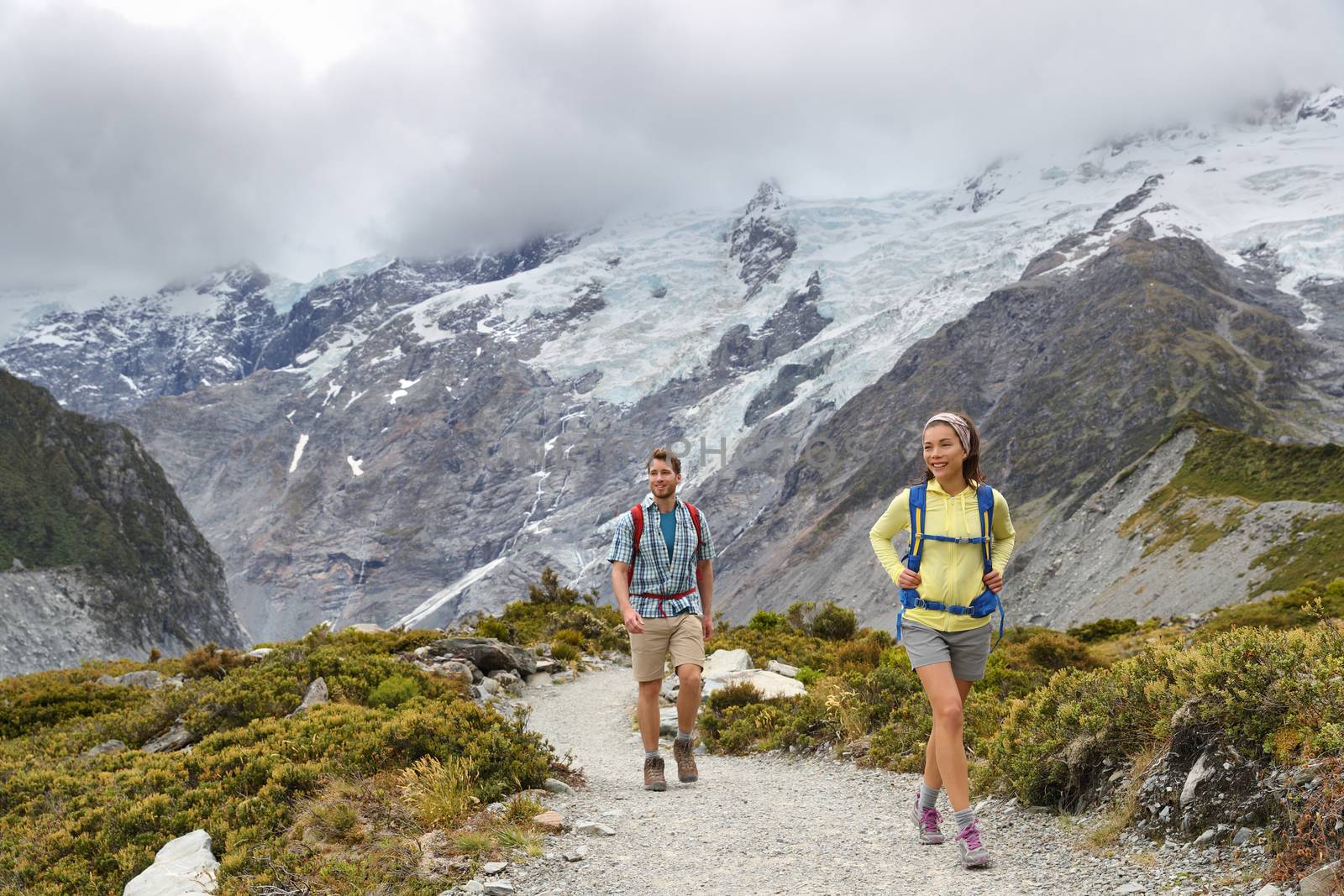 New Zealand backpackers tramping on Mount Cook / Aoraki Hooker valley travel. Backpacking hikers hiking on walking on Hooker Valley Track. Snow capped mountains glacier landscape. Couple on adventure by Maridav