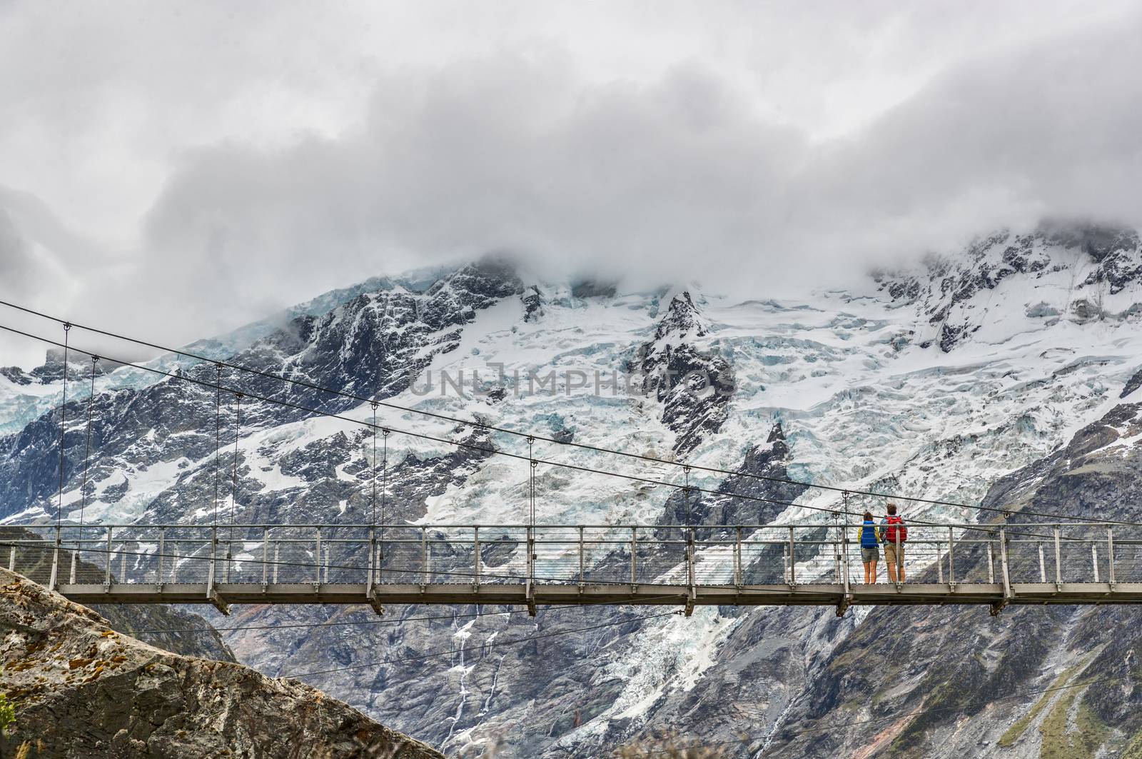Hooker Valley Track hiking trail, New Zealand. Second swing bridge crossing the river on the Hooker Valley track, Aoraki, Mt Cook National Park with snow capped mountains landscape by Maridav
