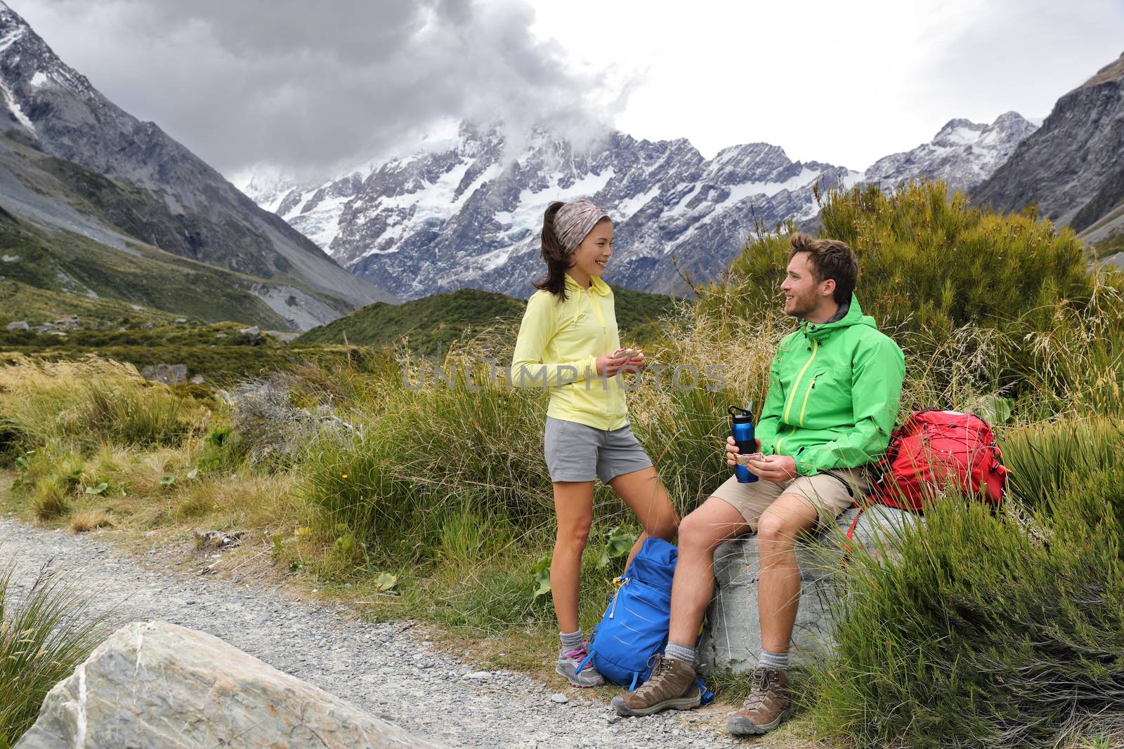 Hikers people eating lunch taking a break during hike on mountain hiking adventure. Tourists relaxing on Hooker Valley track towards Mt Cook on summer travel in New Zealand by Maridav