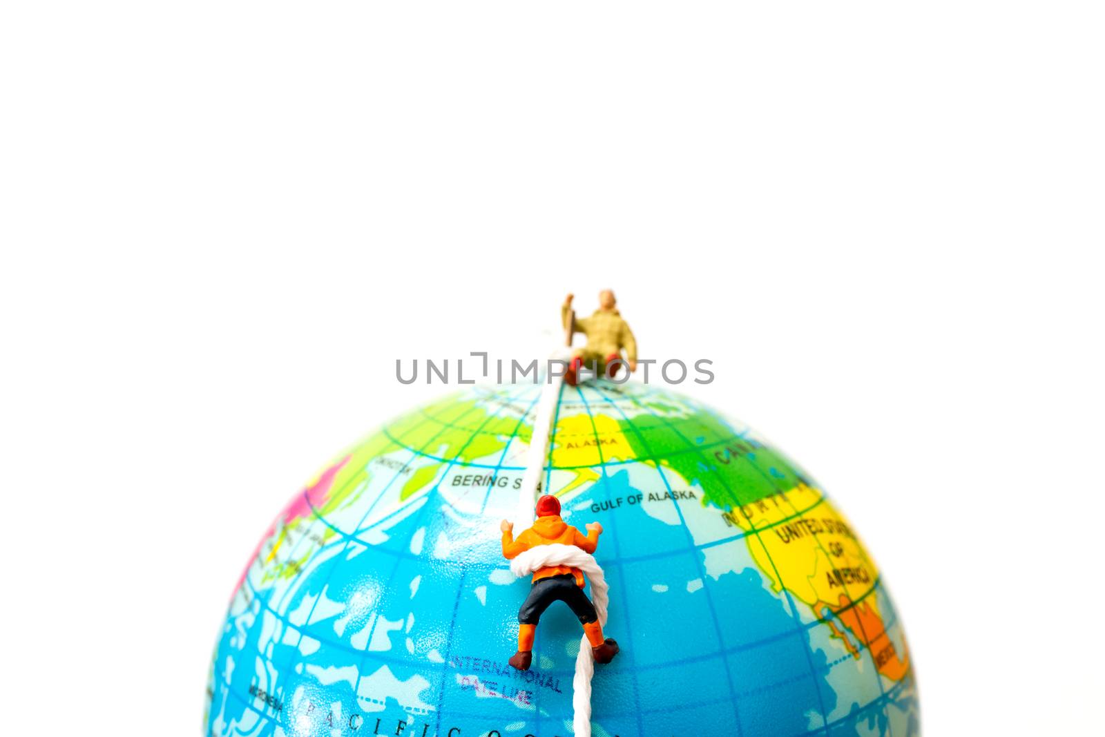 Miniature people: Hikers climbing up on the Globe . Sport and leisure concept.