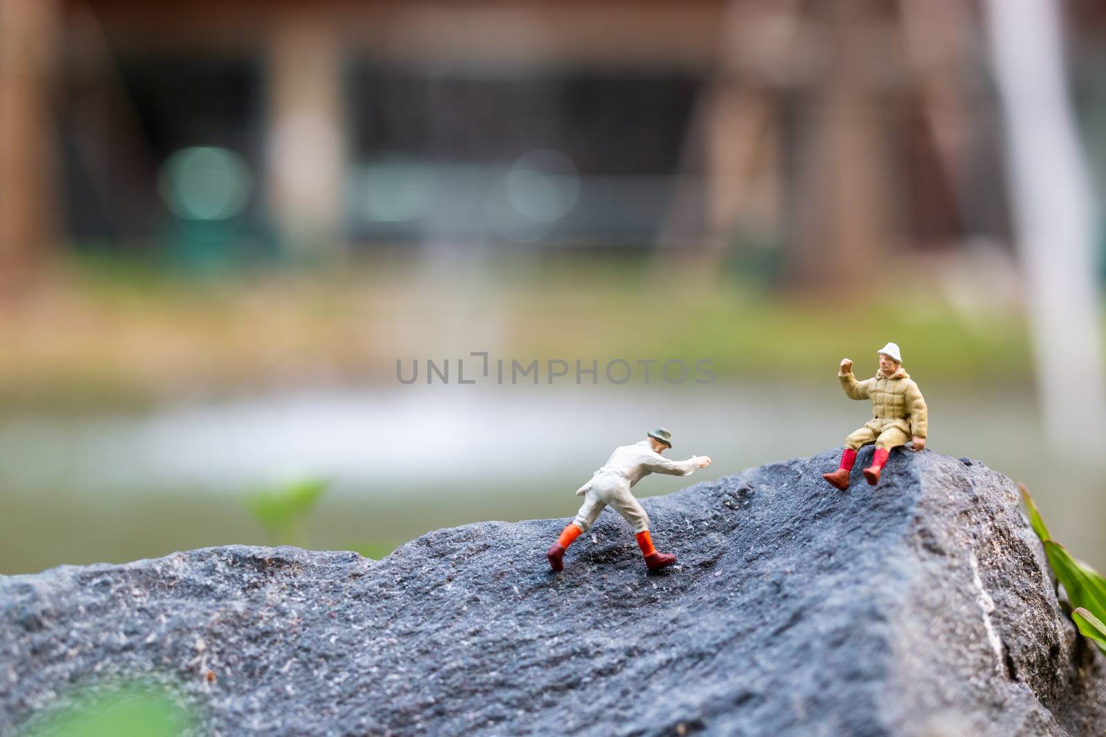 Miniature people: Hikers climbing up on the rock . Sport and leisure concept