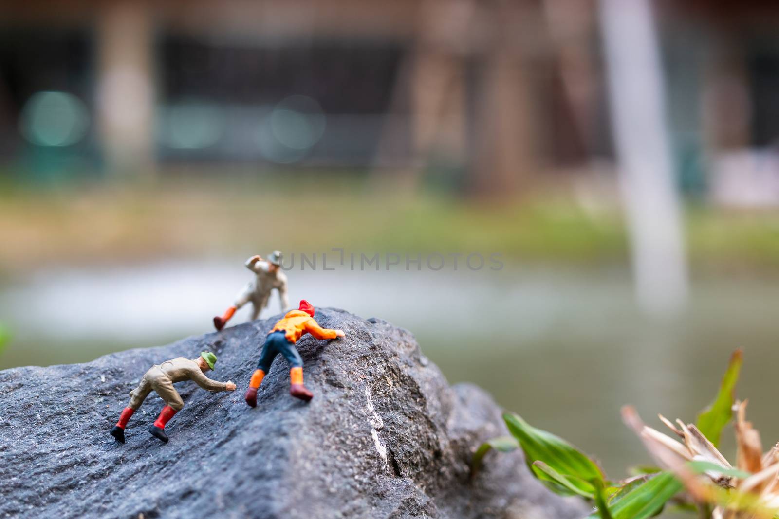 Miniature people: Hikers climbing up on the rock . Sport and leisure concept
