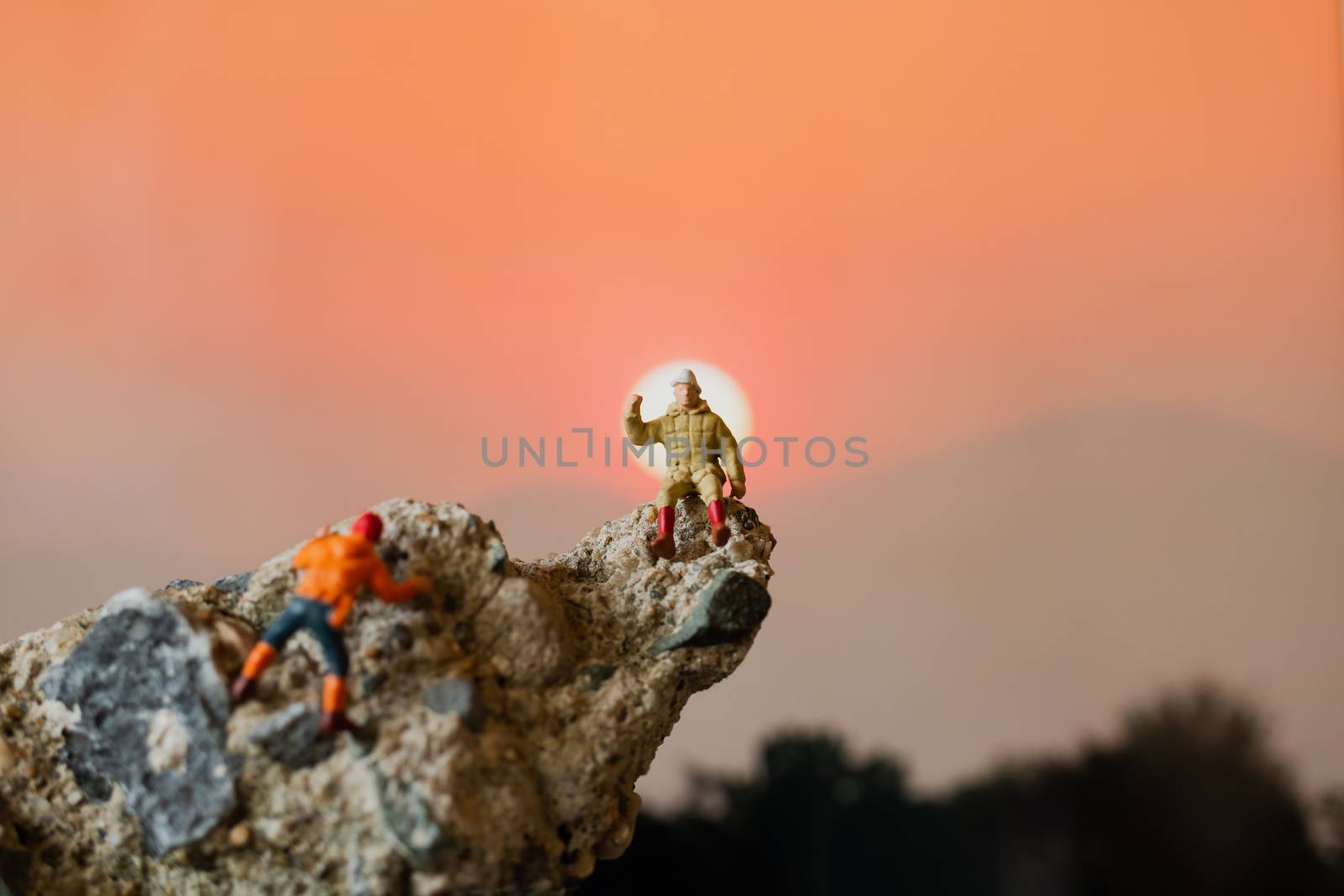 Miniature people: Hikers climbing up on the rock . Sport and leisure concept.