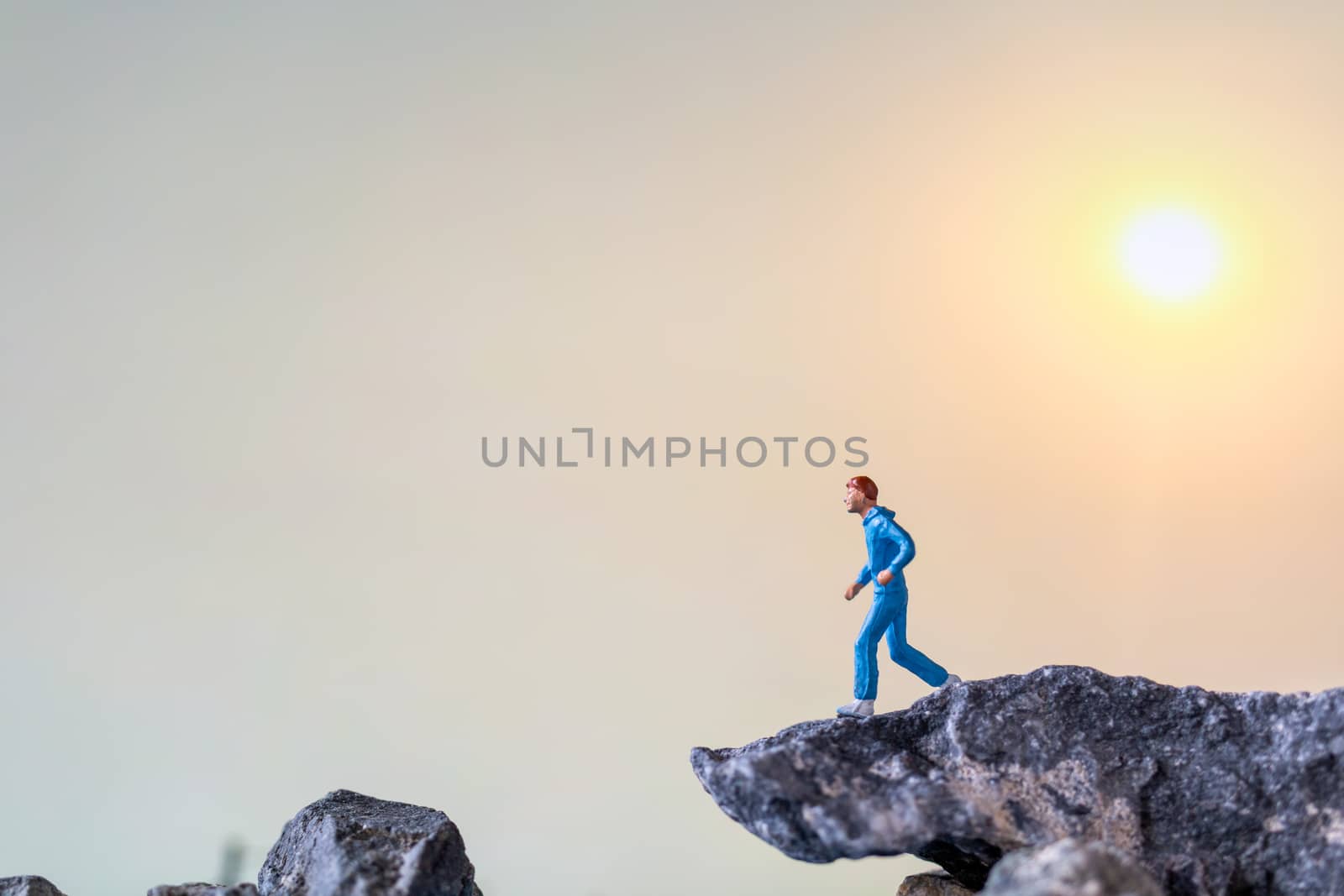 Miniature people : Running on rock cliff with nature background  by sirichaiyaymicro