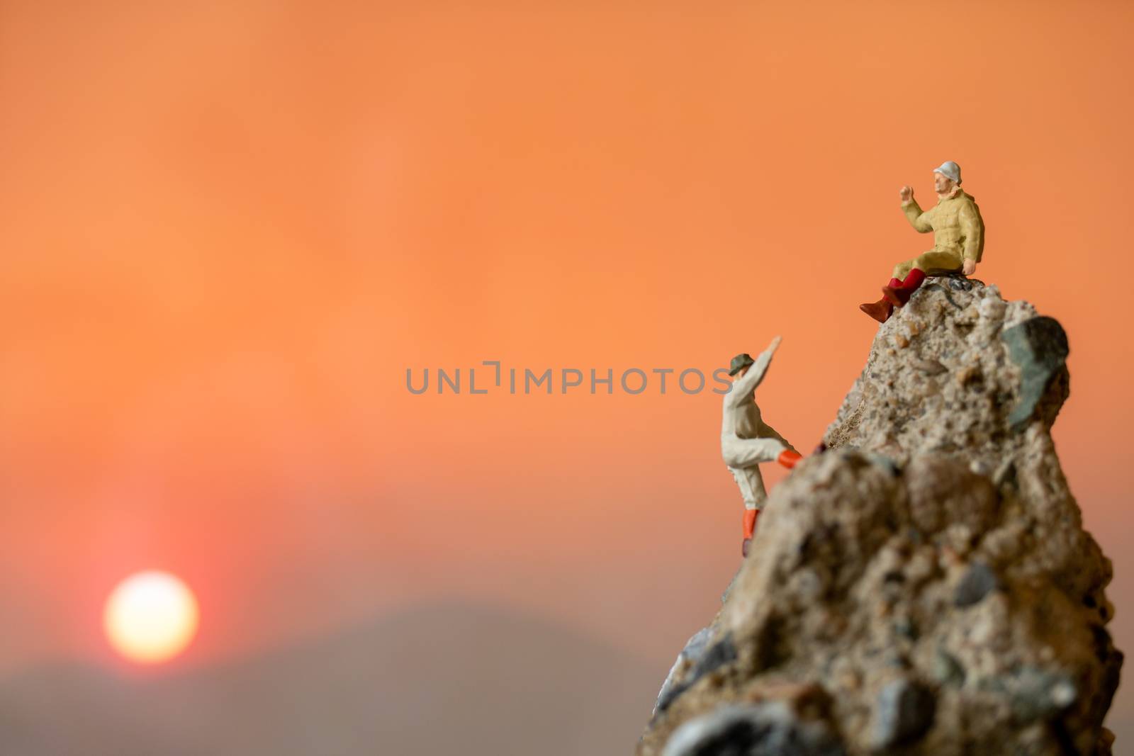 Miniature people: Hikers climbing up on the rock . Sport and leisure concept.