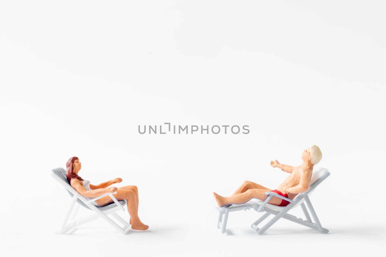 Miniature people sunbathing on deck chairs on white background , Summer time concept