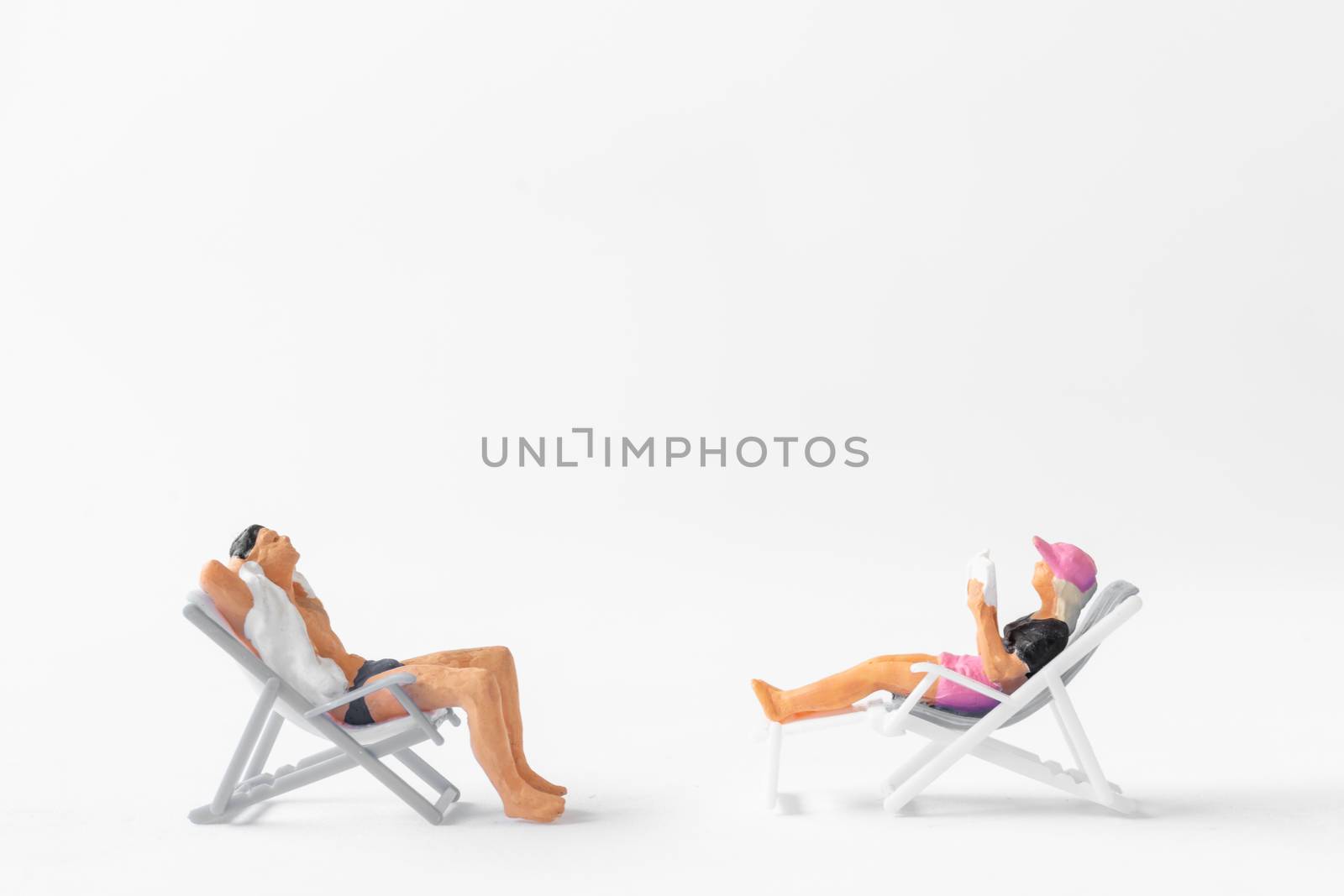 Miniature people sunbathing on deck chairs on white background , Summer time concept