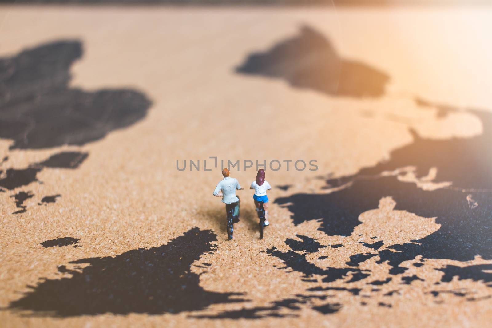 Miniature people travelers riding bicycle on world map , Traveling and exploring the world Concept