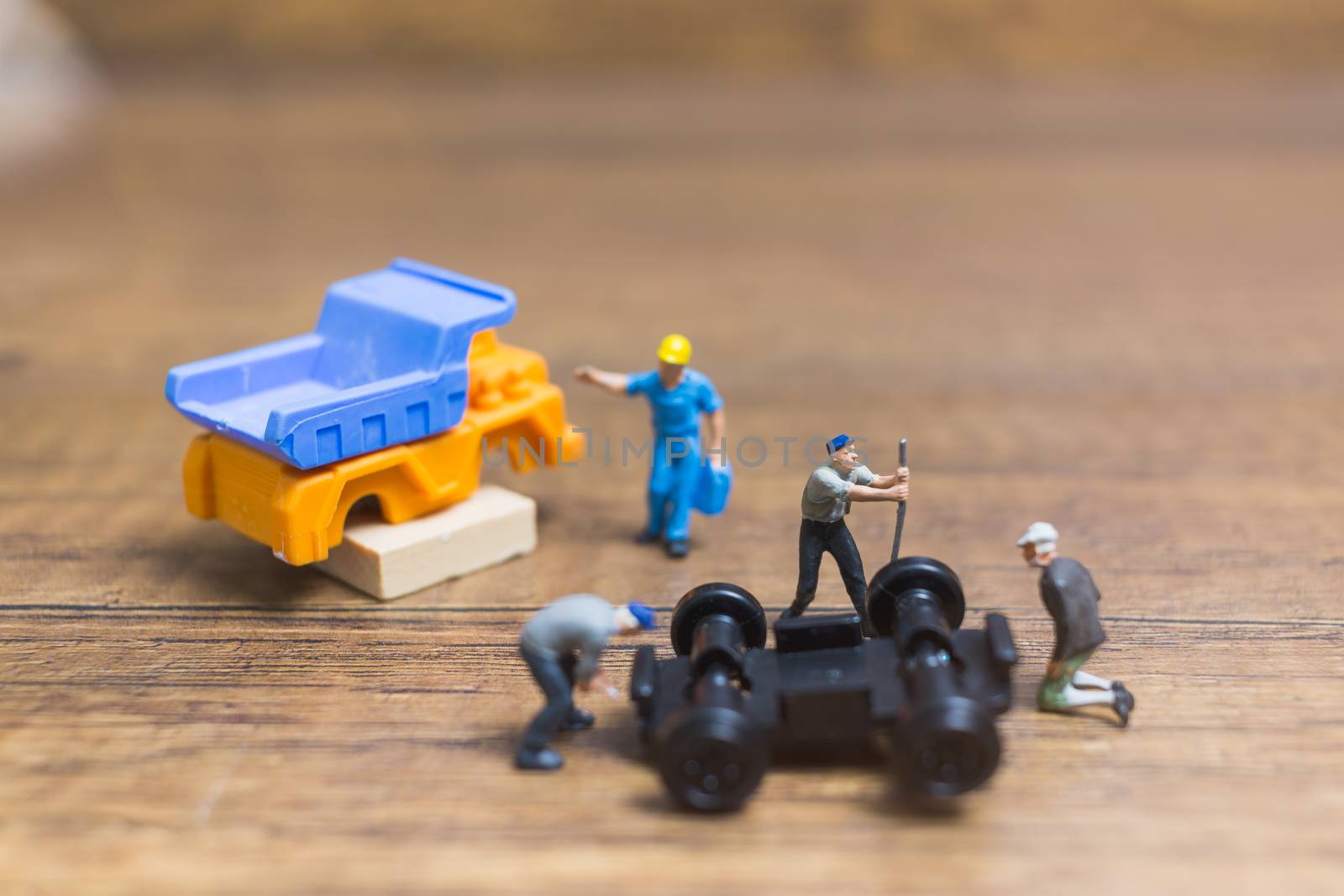 Miniature people : Worker repairing wheel of a truck on wooden background
