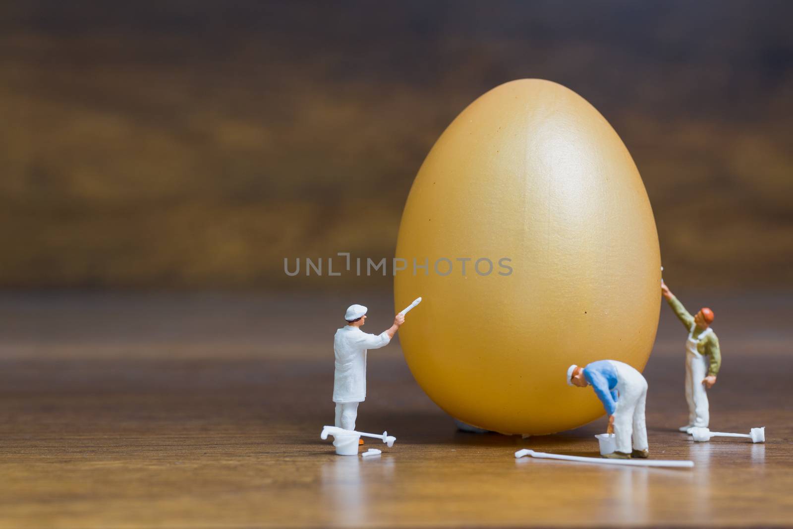 Miniature people :Painter is painting Easter-eggs for Easter day on wooden background