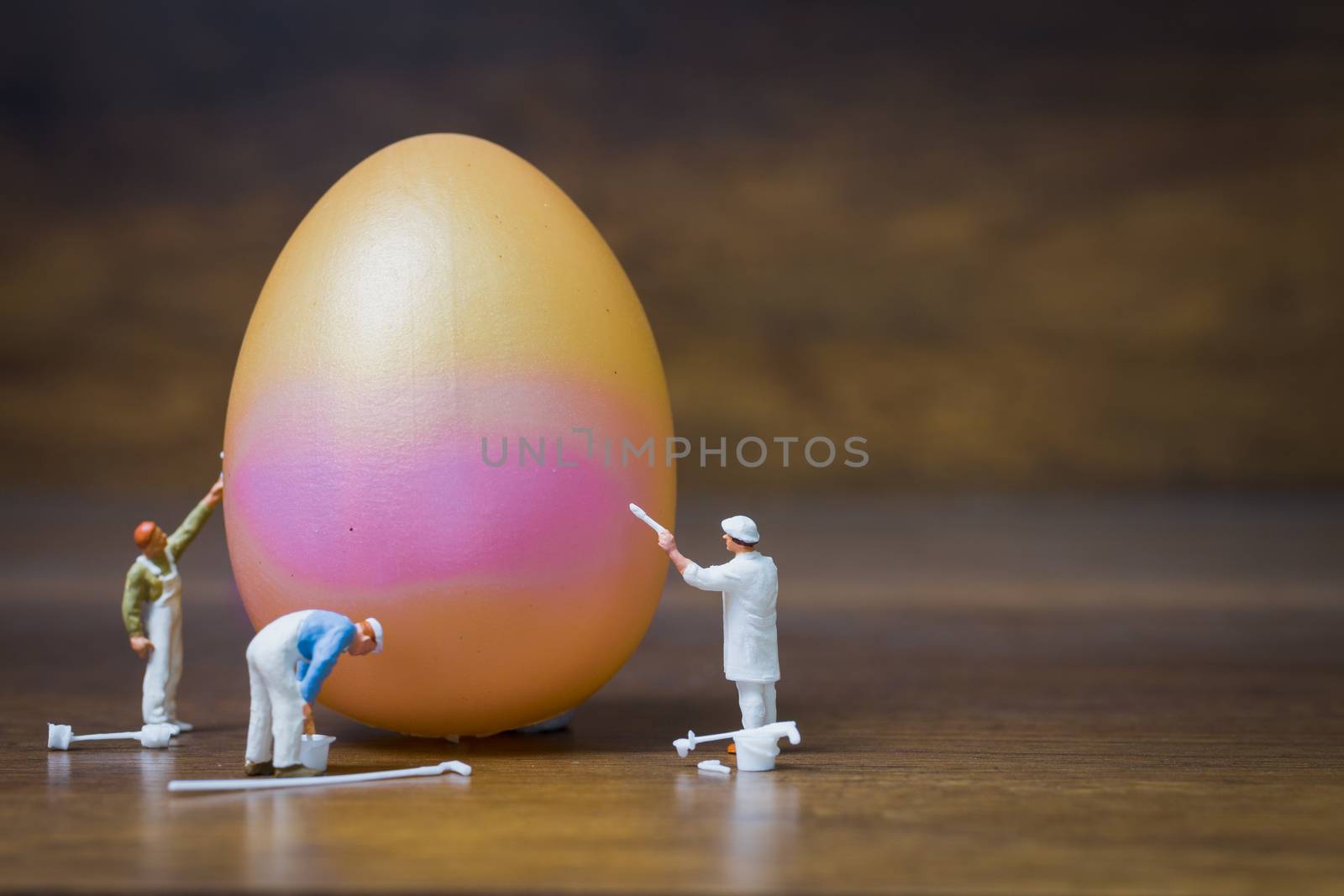Miniature people :Painter is painting Easter-eggs for Easter day on wooden background