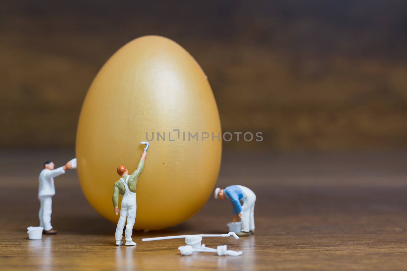 Miniature people :Painter is painting Easter-eggs for Easter day on wooden background