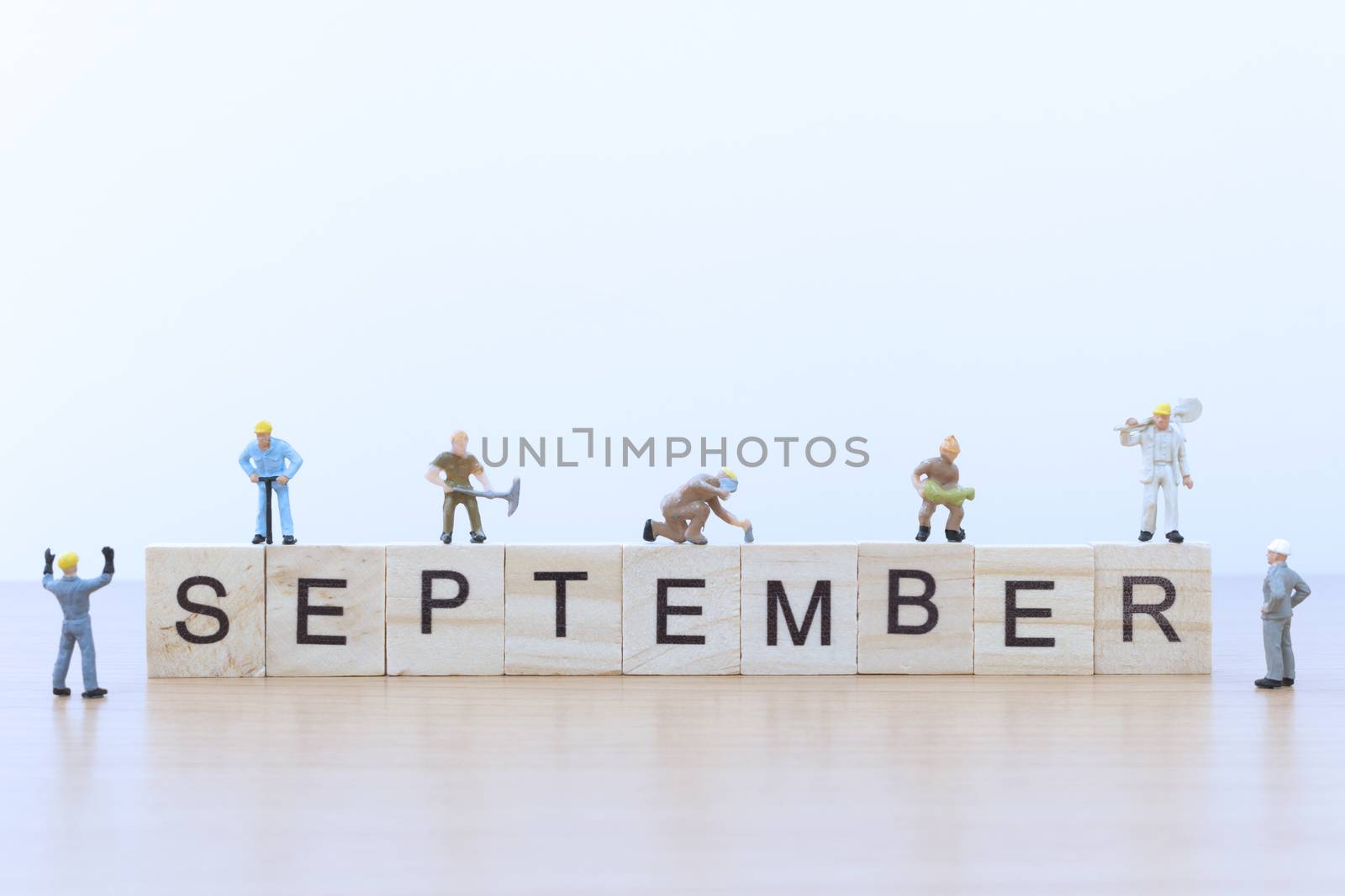 September words with Miniature people worker on wooden floor
