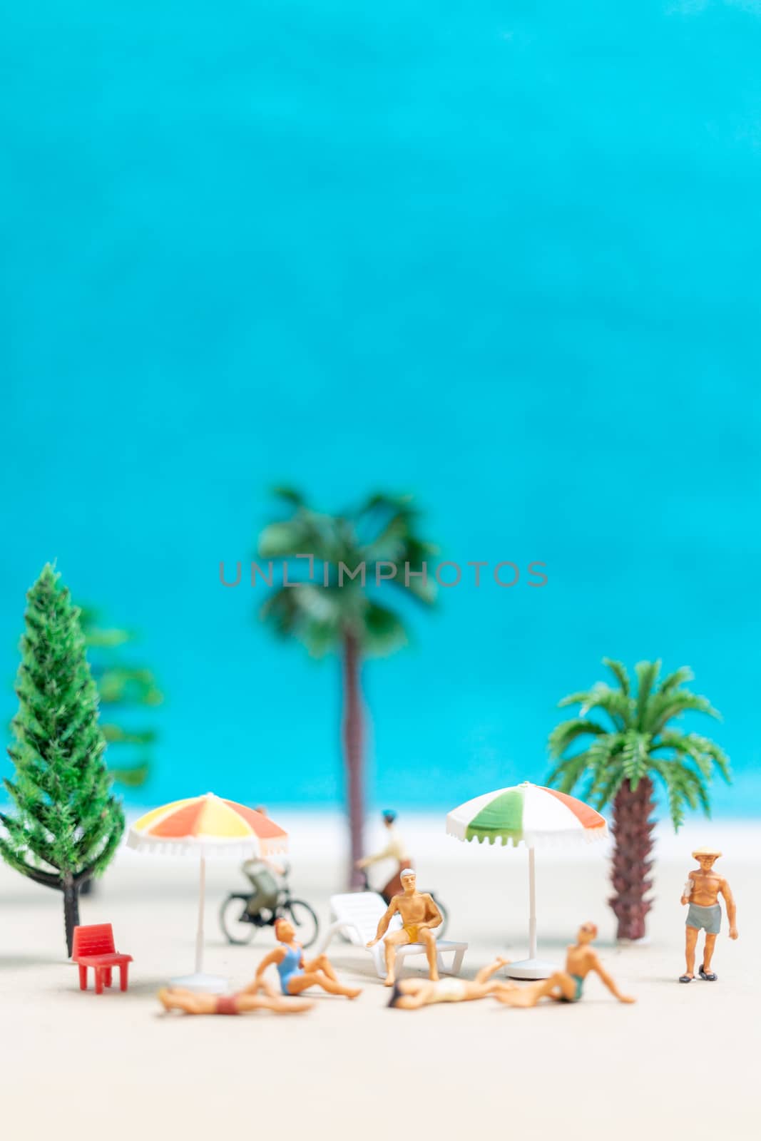 Miniature people wearing swimsuit relaxing on the beach  by sirichaiyaymicro