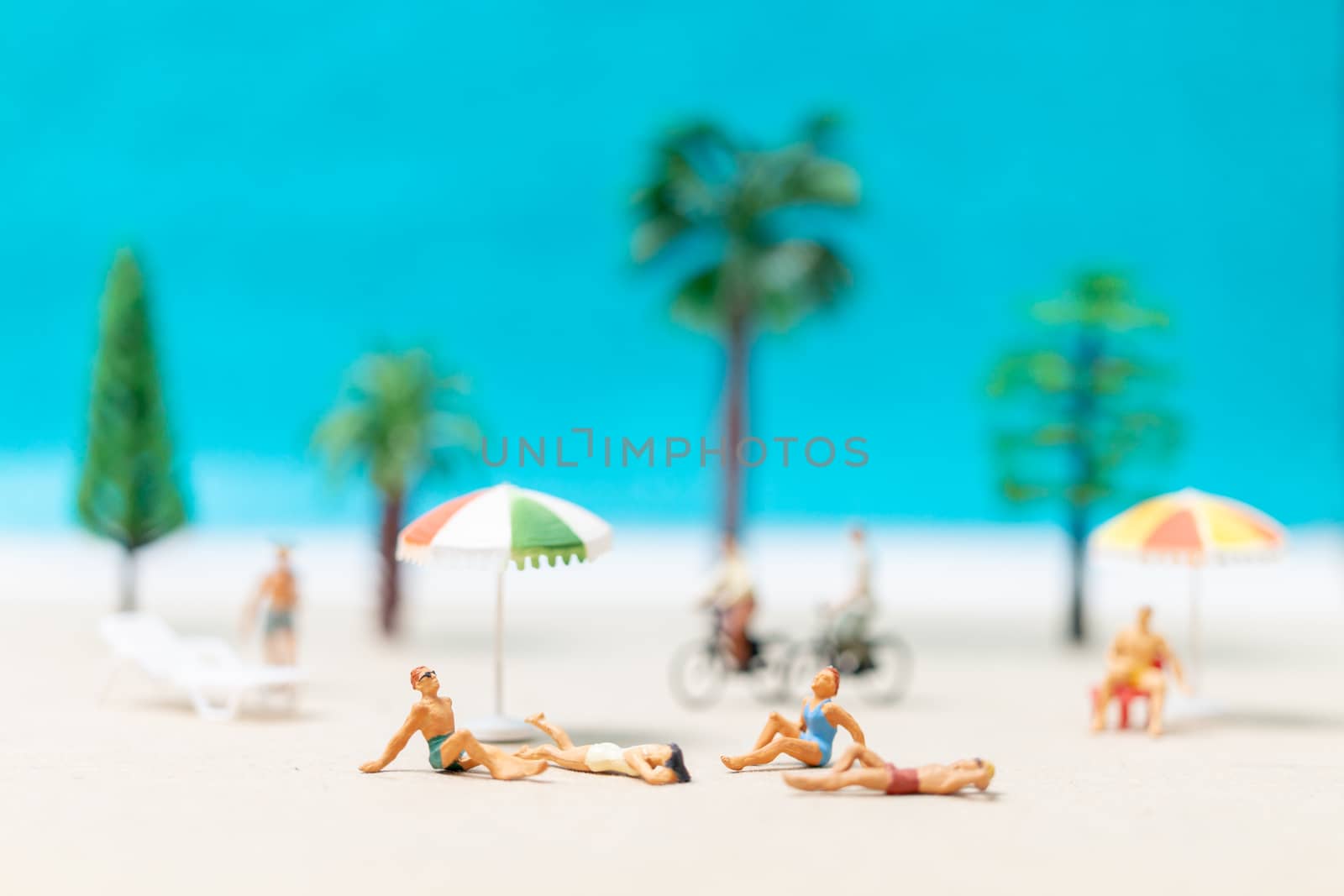 Miniature people wearing swimsuit relaxing on the beach  background