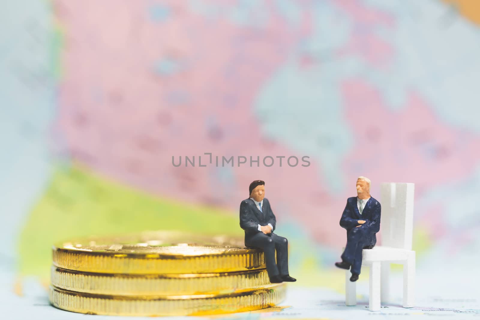 Miniature people: Businessman on stack of coin with world map background , Money and financial business success concept.