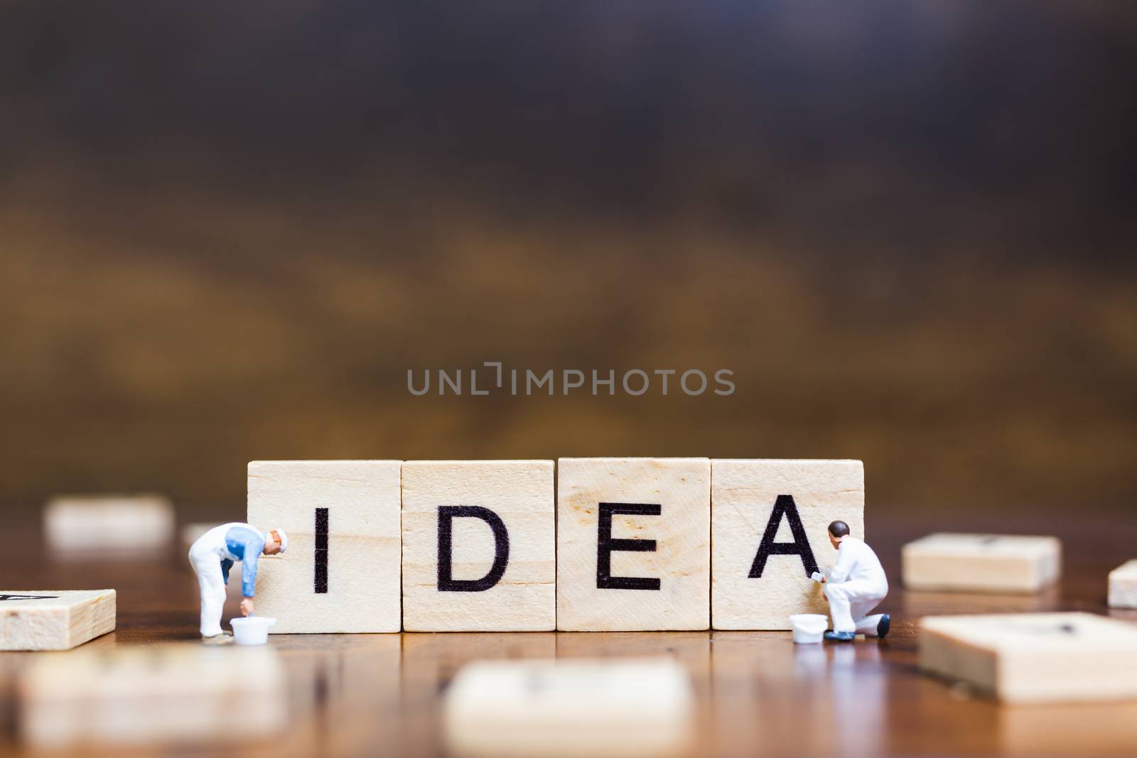 Miniature people standing with wooden block " Idea " words on wooden background