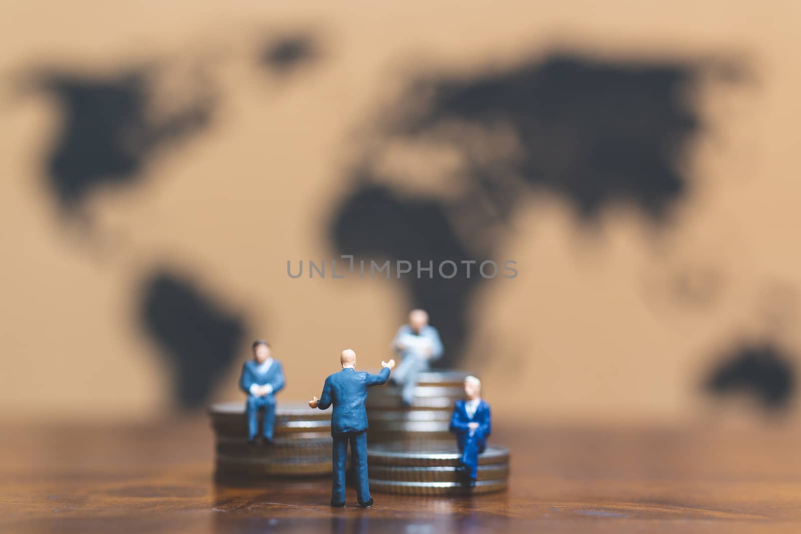 Miniature people: Businessman on stack of coin with world map background , Money and financial business success concept.