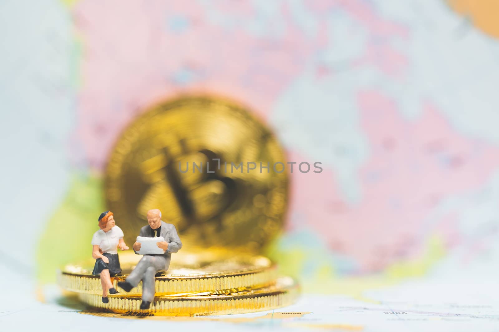 Miniature people: Businessman on stack of coin with world map background , Money and financial business success concept.