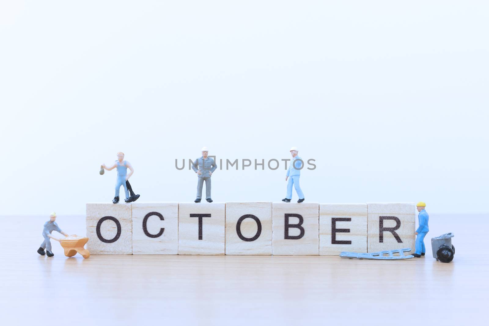 October words with Miniature people worker on wooden floor
