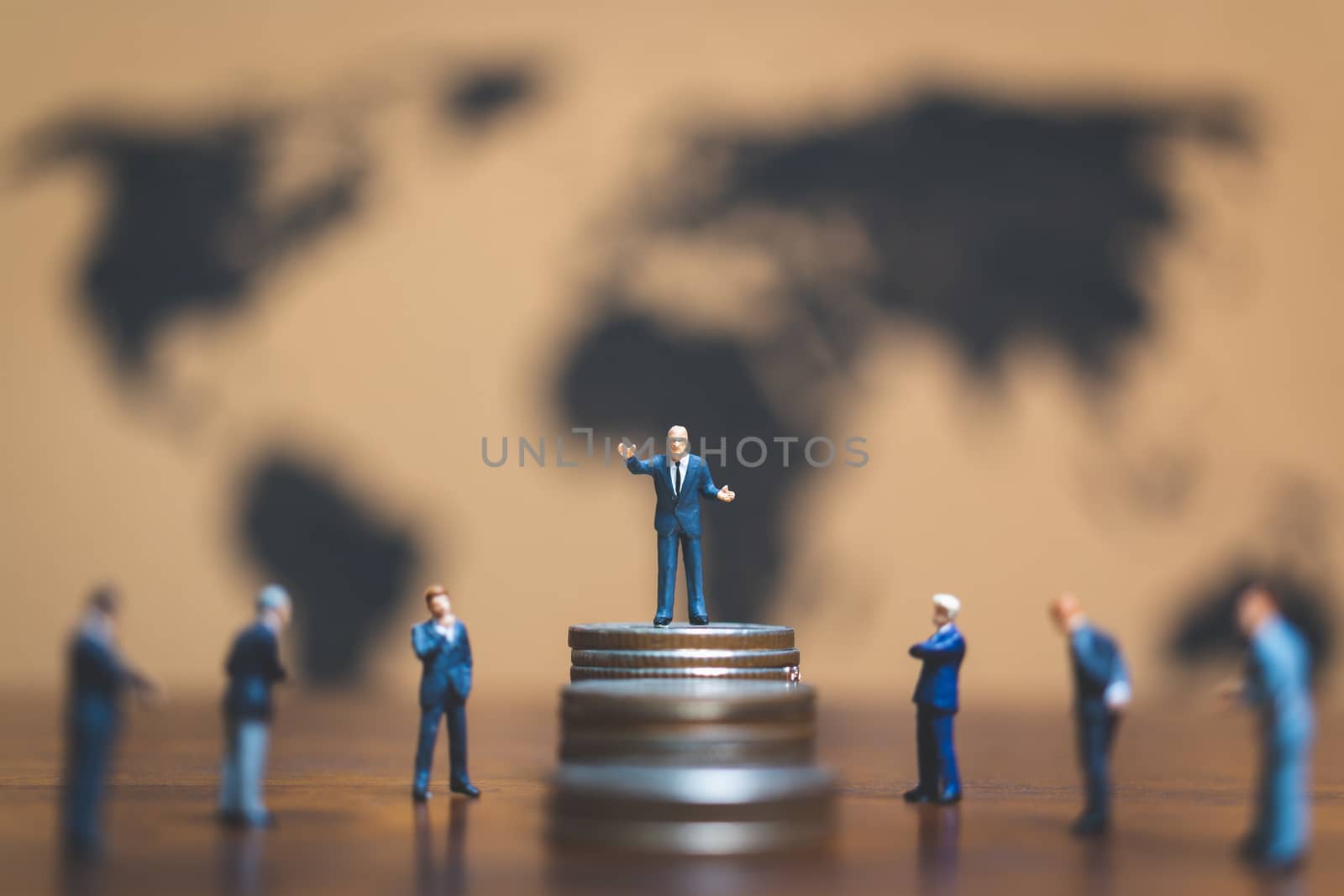 Miniature people: Businessman on stack of coin with world map background , Money and financial business success concept.