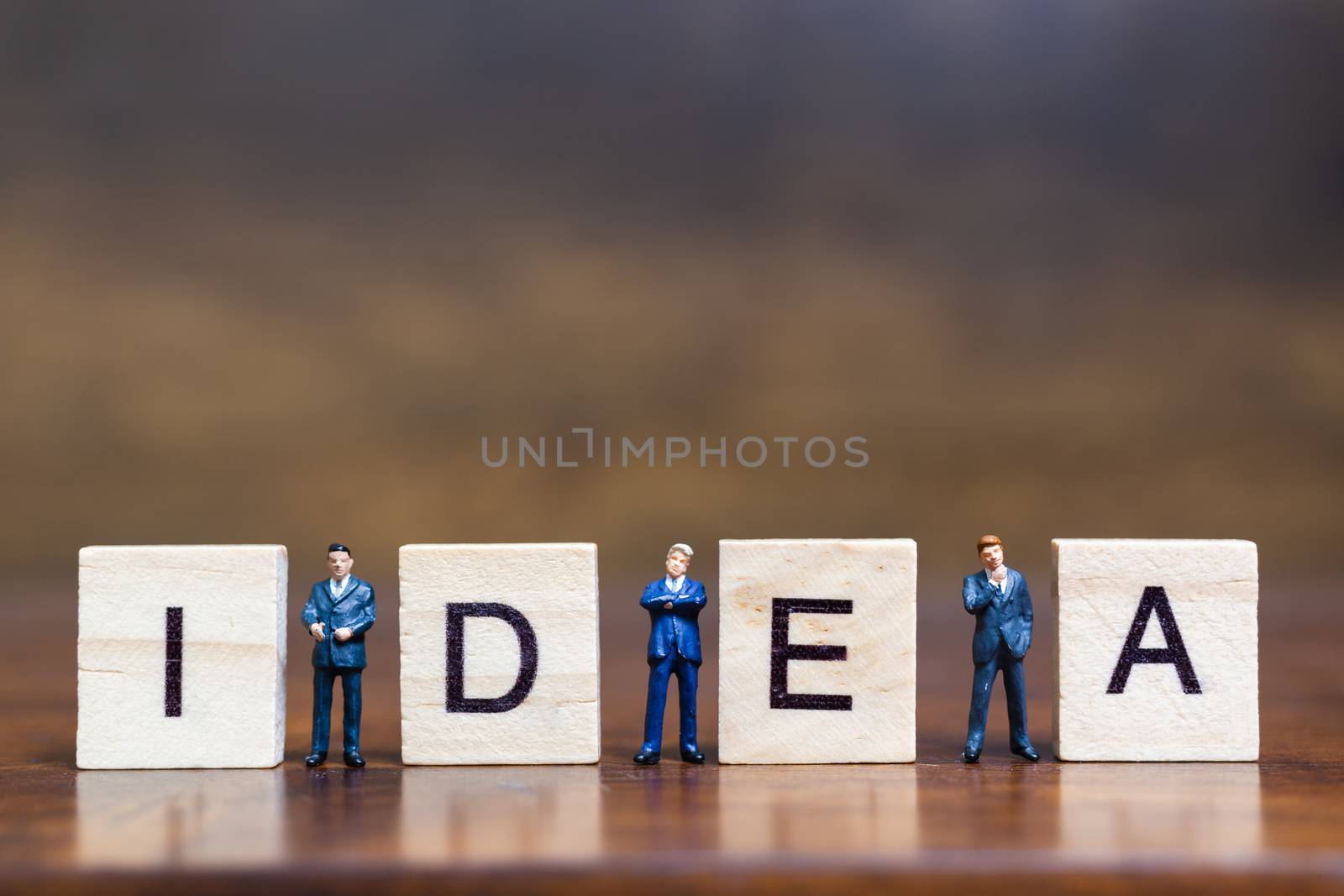 Miniature people standing with wooden block " Idea " words on wooden background