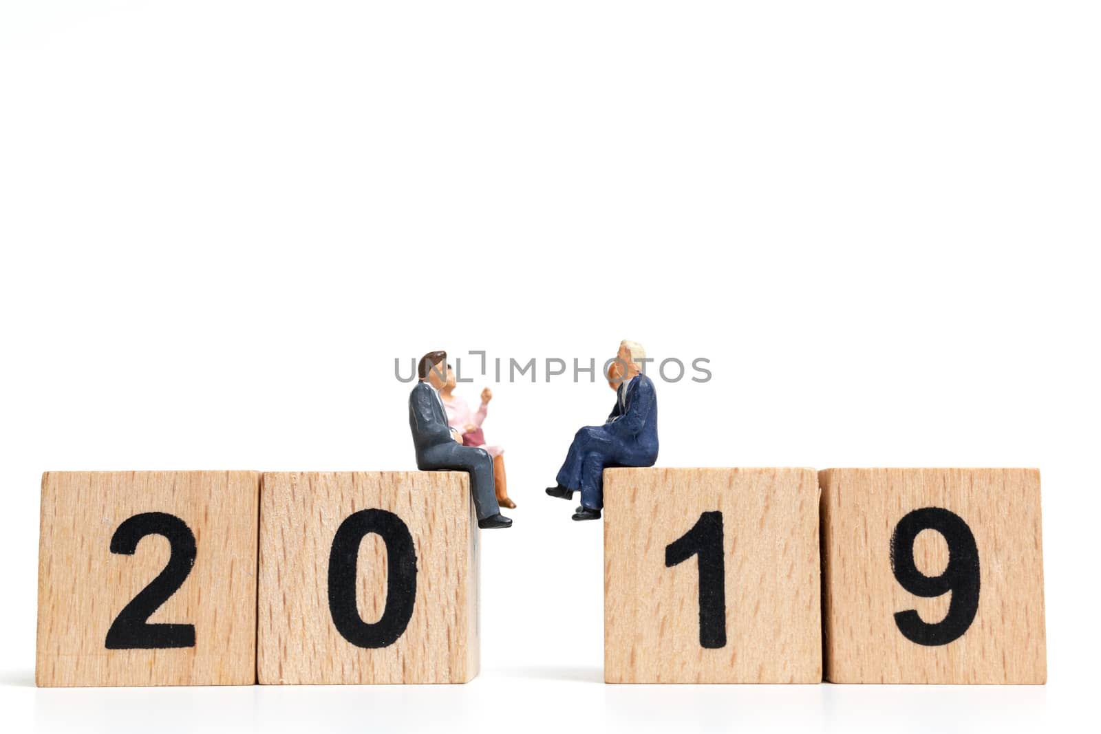 Miniature people sitting on wooden block number 2019. on white background