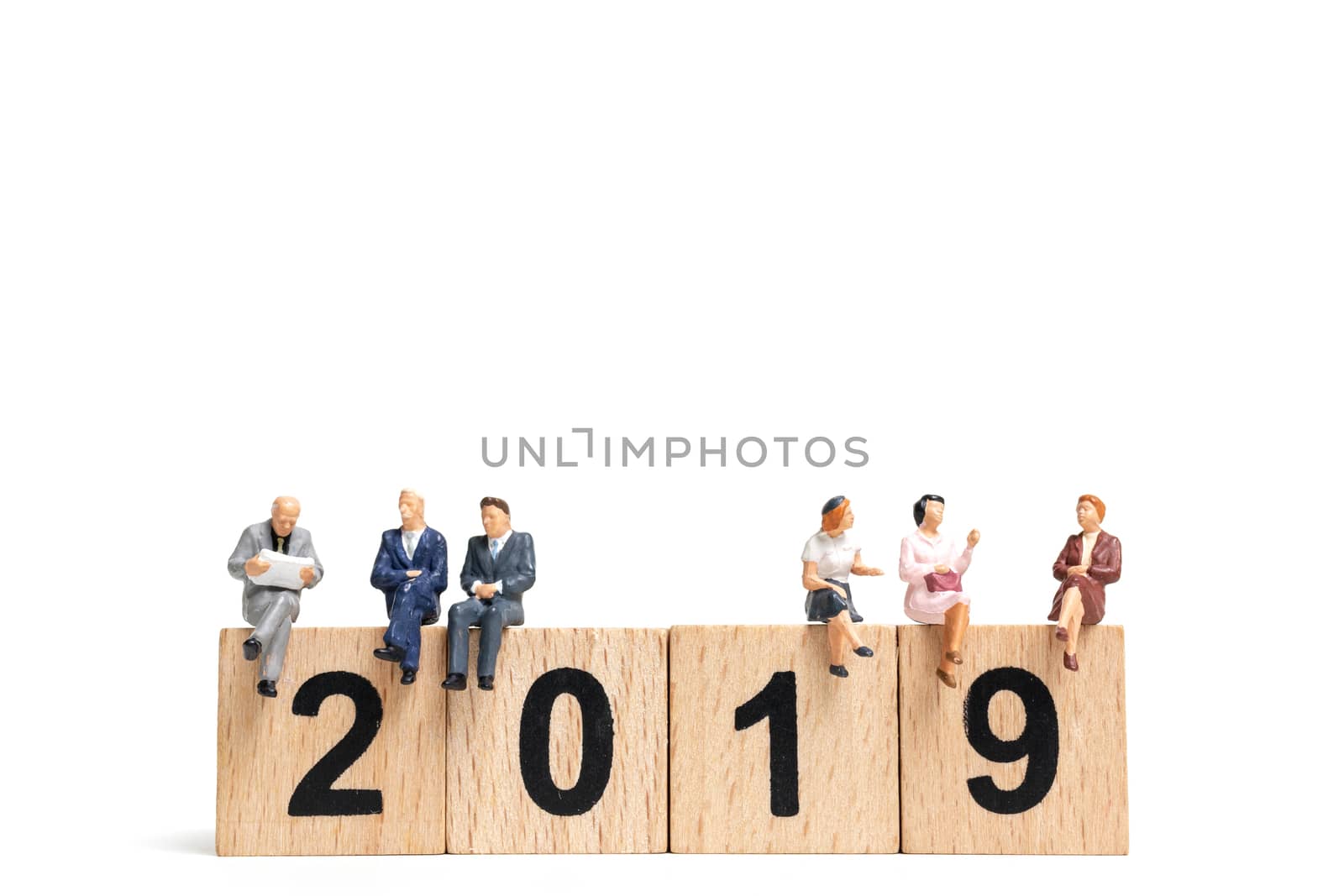 Miniature people sitting on wooden block number 2019. on white background