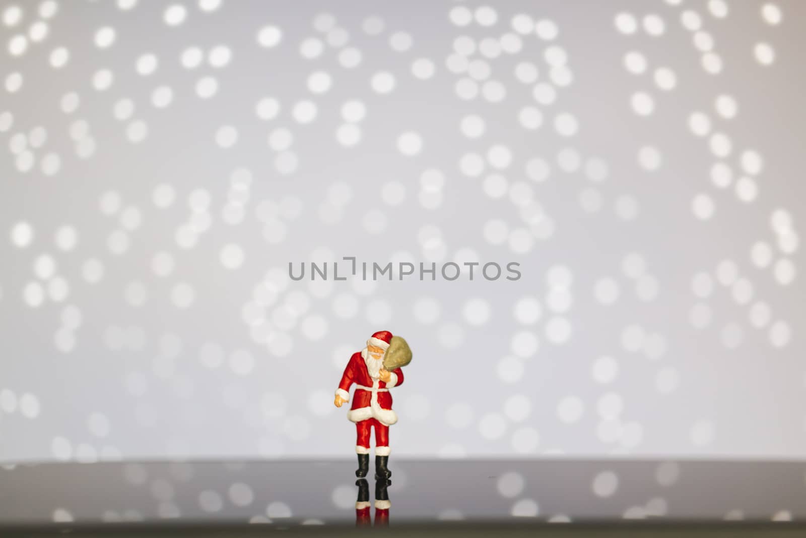 Miniature people : Santa Claus carrying bag  on bokeh  background , Merry Christmas and Happy New Year concept.